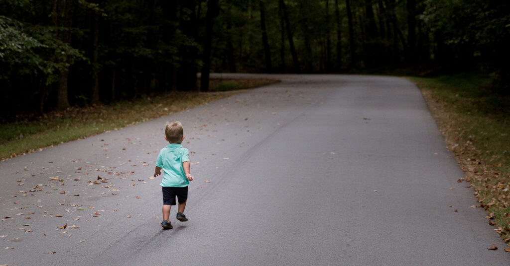 Toddler walking down a road